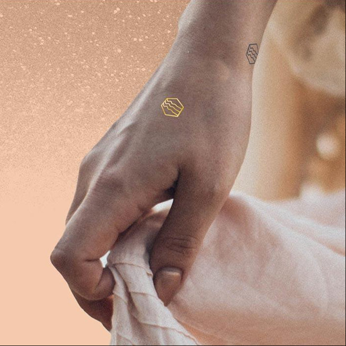 Woman holding dress with mindfulness temporary tattoos on her wrist and hand that represent feeling your emotions.