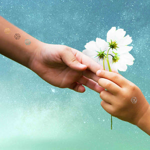 Woman reaching out to receive a flower from a child. Both are wearing mindfulness temporary tattoos.