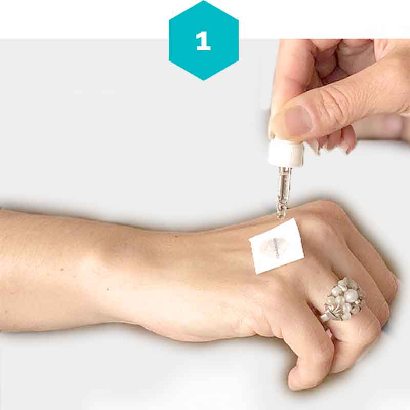 A woman has selected her intention and applies her mindful mark face down with water on her hand using a water dropper.