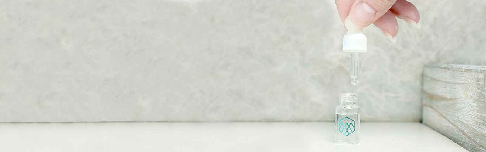 Woman holding the top of a tiny water dropper. 