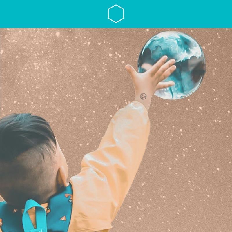 Little boy reaching for a bubble with a Play Mindful Mark on his wrist.