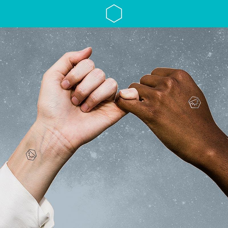 Two hands holding each other's pinky wearing Align Mindful Marks on their wrists.