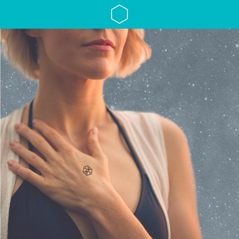 Woman holding hand over heart wearing mindfulness temporary tattoo that represents the intention to listen.
