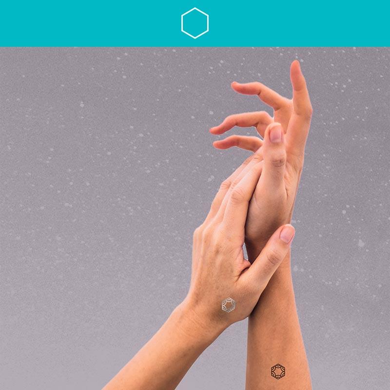 A woman wearing mindful marks is lightly touching her palm to the wrist of her other hand.