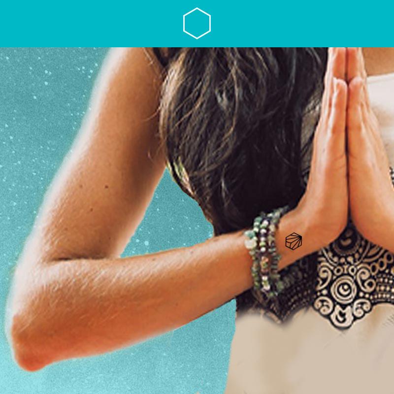 Woman holding palms together in front of chest wearing intention temporary tattoo on wrist.